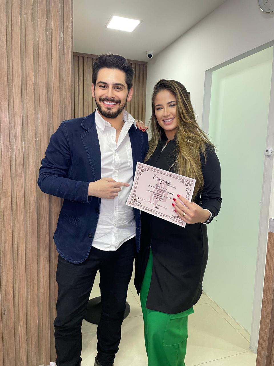 Dr. Lopez ao lado de aluna segurando certificado da formação presencial