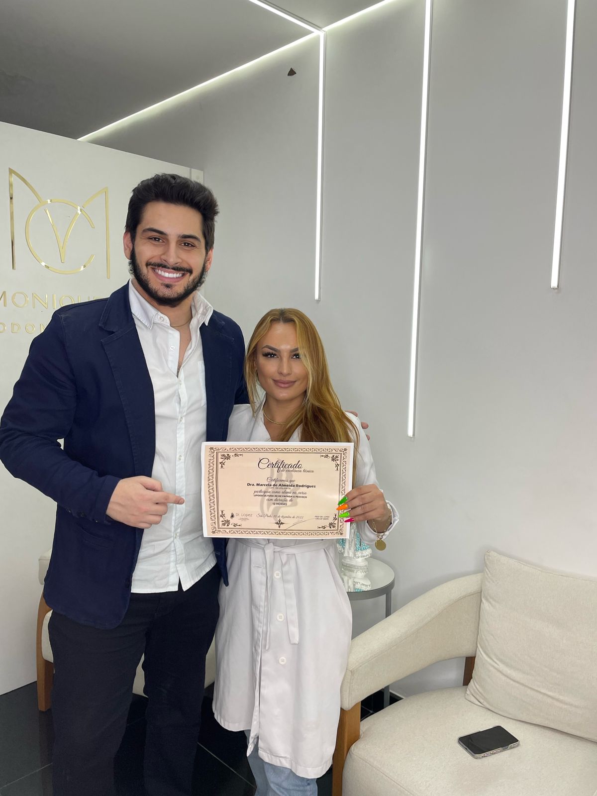 Dr. Lopez ao lado de aluna segurando certificado de lipoescultura de papada e pescoço