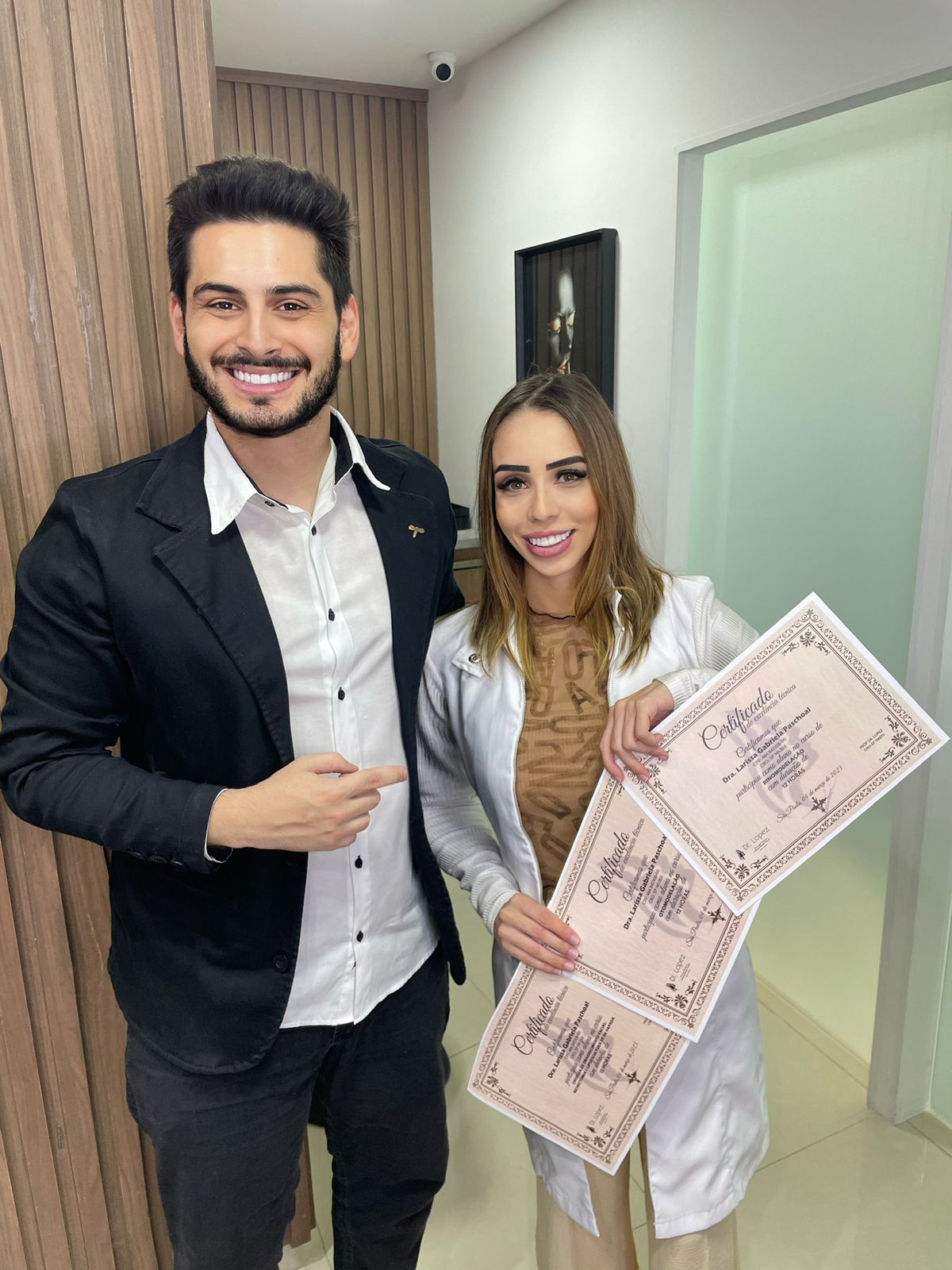 Dr. Lopez ao lado de aluna segurando três certificados de otomodelação
