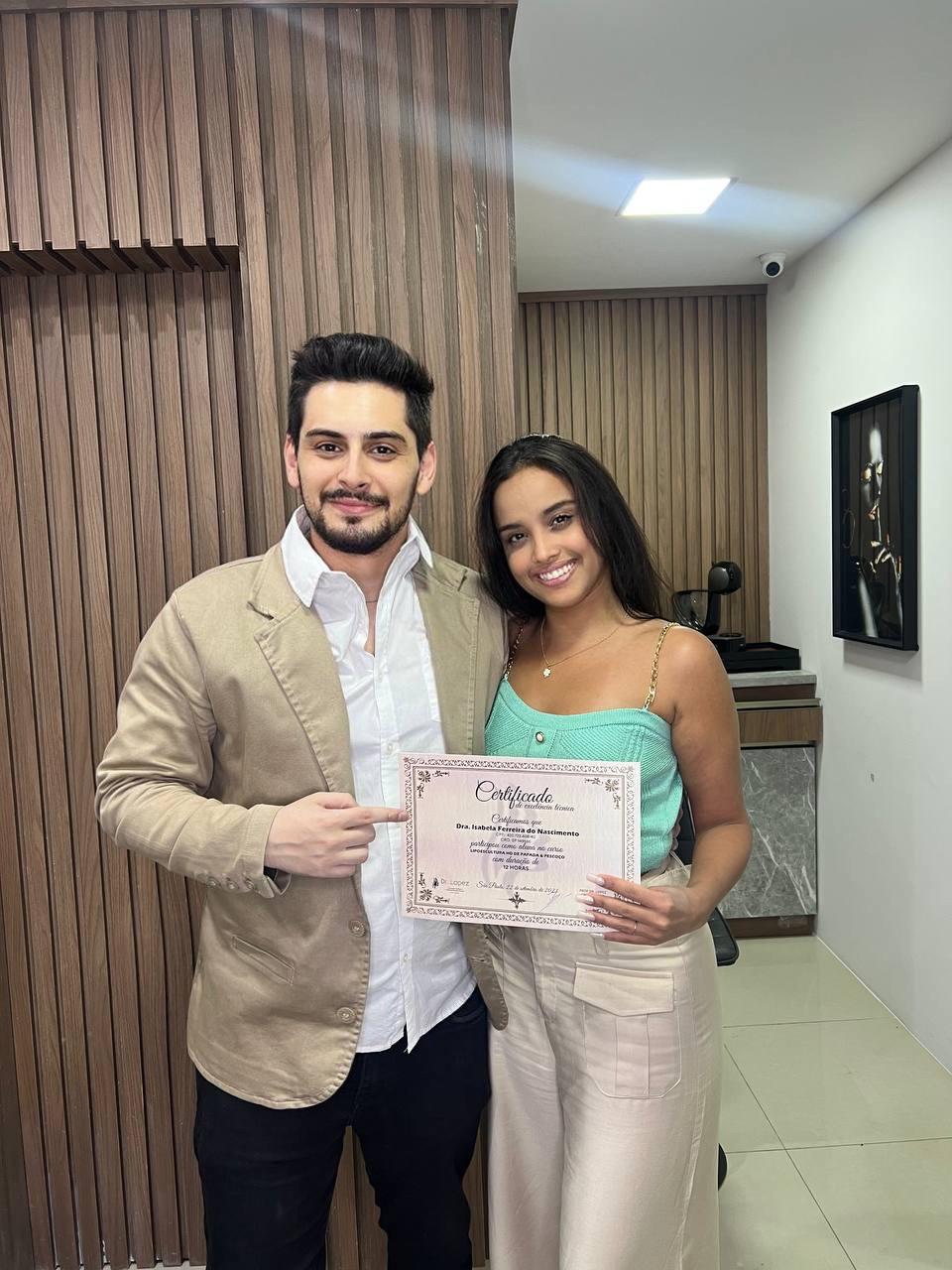 Dr. Lopez ao lado de aluna segurando certificado de lipoescultura de papada e pescoço
