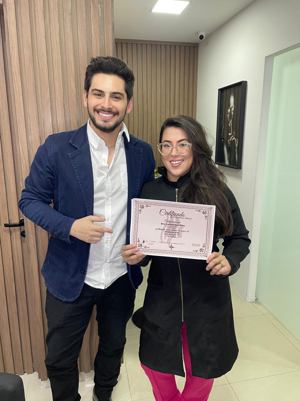 Dr. Lopez ao lado de aluna segurando certificado de otomodelação